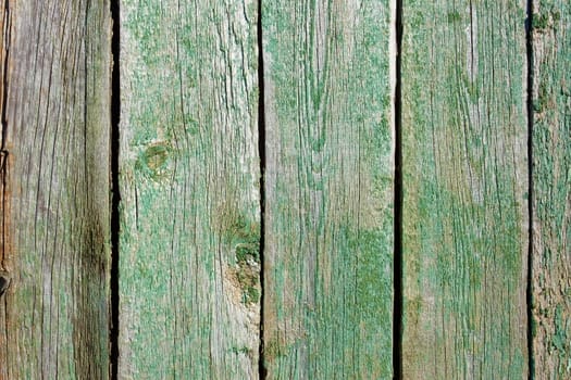 Shield of several parallel old wooden boards with very ragged green paint