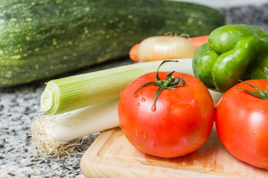 Fresh vegetables on cutting board in the kitchen over granite worktop