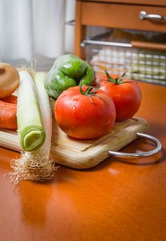 Fresh vegetables on cutting board in a wooden kitchen table