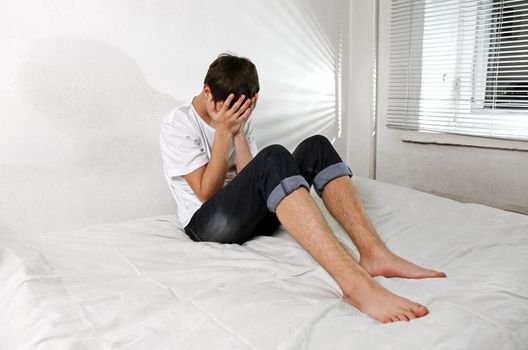 Sorrowful Young Man sitting on the bed Alone