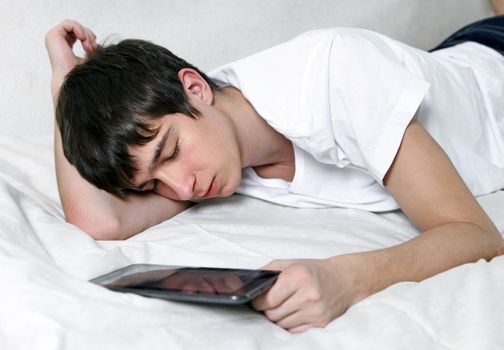 Tired Young Man Sleeps with Tablet Computer on the bed