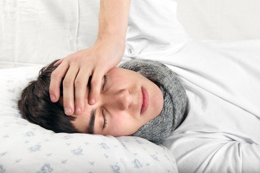 Diseased Young Man lying on the Bed and feels Headache