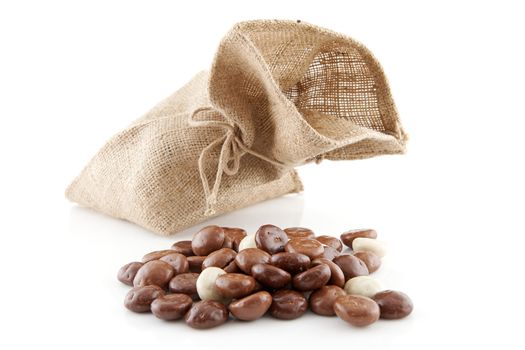Jute bag with typical dutch sweets: chocolate pepernoten (ginger nuts) for a celebration at 5 december in the Netherlands over white background