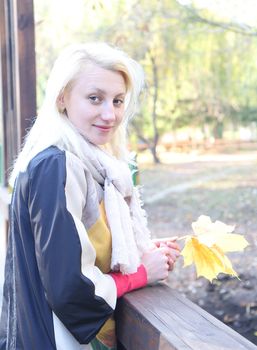 Cute blond  girl  with maple leaf smiling. Autumn