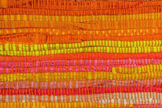 Textile background in red, yellow, orange, pink and green manually weaved