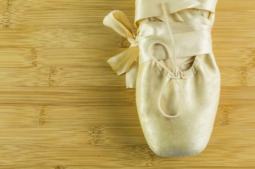 Detail of a ballet shoes on a wooden background