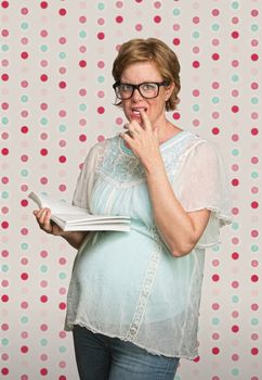 Confused young pregnant woman on polka dot background
