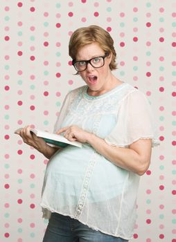 Astonished single pregnant female pointing at a book