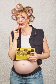 Depressed pregnant hick eating from box of chocolates