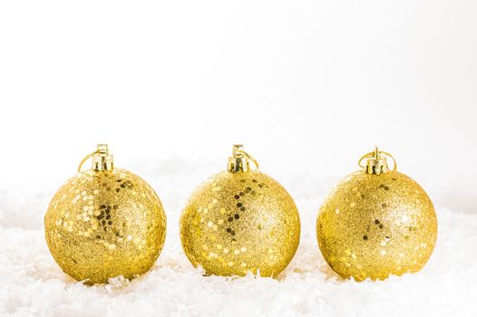 Three golden christmas decorations on artificial snow