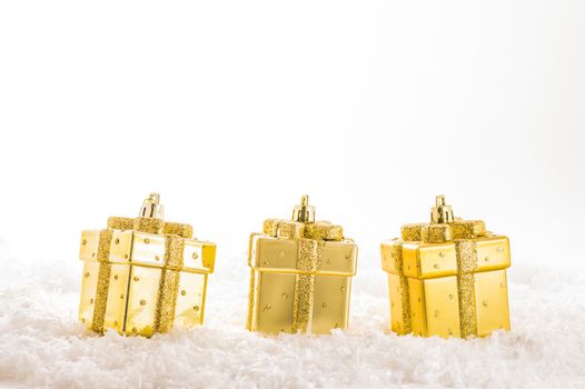 Three golden christmas decorations on artificial snow