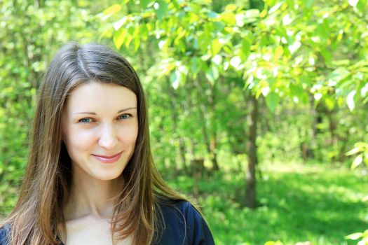 young beautiful smiling girl on a background of green vegetation