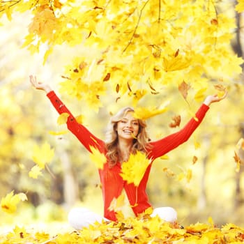 Happy woman in autumn park drop up leaves