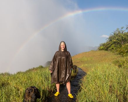 Victoria Falls (or Mosi-oa-Tunya - the Smoke that Thunders) waterfall in southern Africa on the Zambezi River at the border of Zambia and Zimbabwe. Female tourist faces camera in wet spray