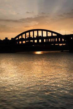 Sunset cityscape with silhouette of bridge under golden dramatic sky in Taipei, Taiwan, Asia.