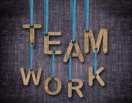 Team work Letters hanging strings with blue sackcloth background.