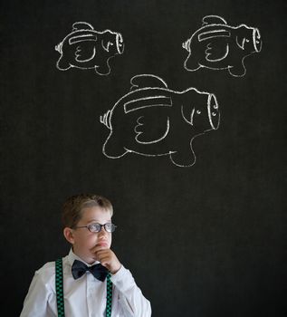 Young business boy thinking with flying money piggy banks in chalk on blackboard background