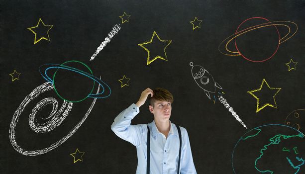 Businessman scratching head with chalk universe planet solar system on blackboard imagining space travel