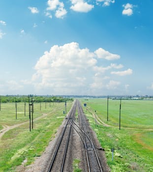 railroad in green landscape under clouds