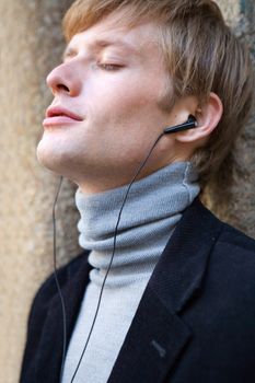 attractive man in urban background listening to music with earphones