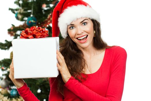 A happy surprised woman wearing a Santa hat and holding a big white Christmas present with room for copy space. Isolated on white.