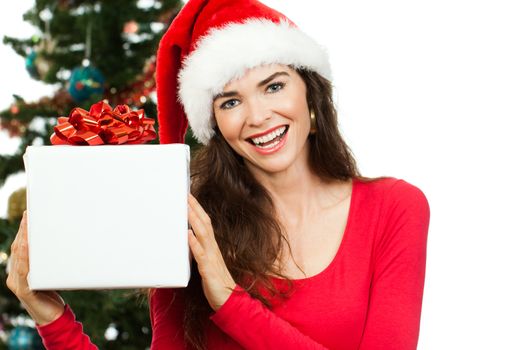 A happy beautiful woman wearing a Santa hat and holding a big white Christmas present with room for copy space. Isolated on white.