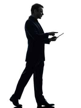 one caucasian business man walking touchscreen digital tablet   in silhouette on white background