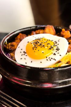 close up bibimbap with fried egg  , mix vegetable and meat in a heated stone bowl ,  korean style cuisine 