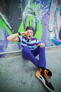 Happy teens boy with headphones near painted wall listening to music