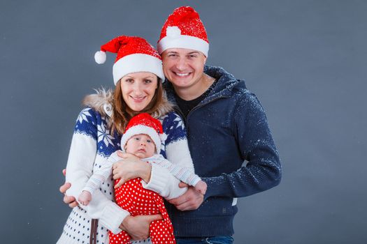 Christmas theme - Portrait of happy family with baby in Santa's hat in studio