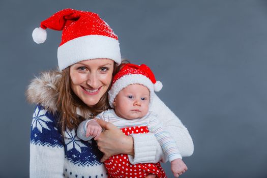 Christmas theme - Portrait of happy mother with babyboy in Santa's hat in studio