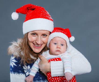 Christmas theme - Portrait of happy mother with babyboy in Santa's hat in studio