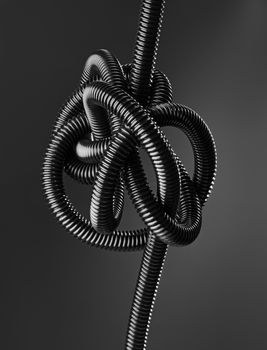 Black and white image of a black tangled flexible hose.