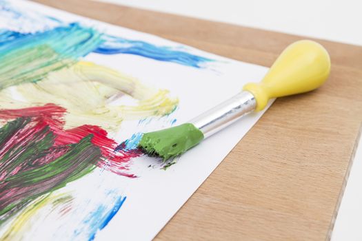 green paint with paint brush  and paper on wooden table