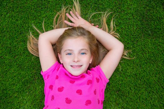 Beautiful blond kid children girl smiling relaxed lying on grass backyard lawn