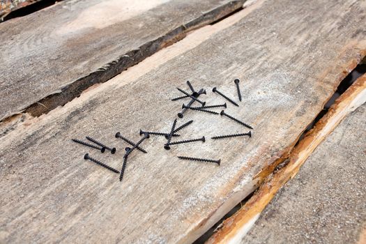 Self-tapping screws for wood in black on the background of several boards and sawdust