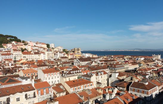 Old houses and roofs in cityscape of Alfama district of Lisbon in Portugal with the coast in the distance