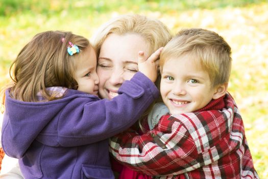 Two children hugging mother, focus on boy