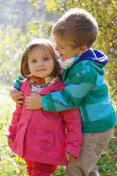 Happy brother hugging sister in autumn park