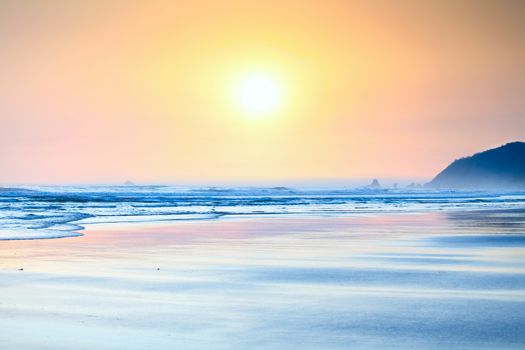 Beautiful yellow orange sunset over   gentle waves washing up on beach