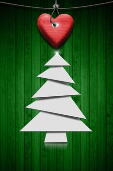 White stylized Christmas tree and handmade red wooden heart hanging on a steel cable on green wooden background