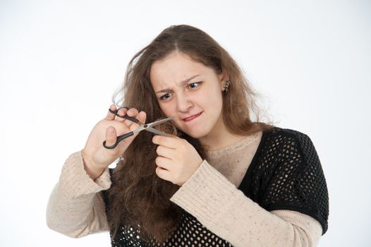 woman mows split ends of hair with scissors