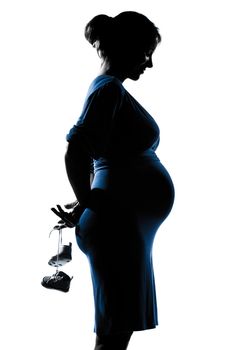 beautiful caucasian pregnant woman holding baby shoes in silhouette on studio isolated white background