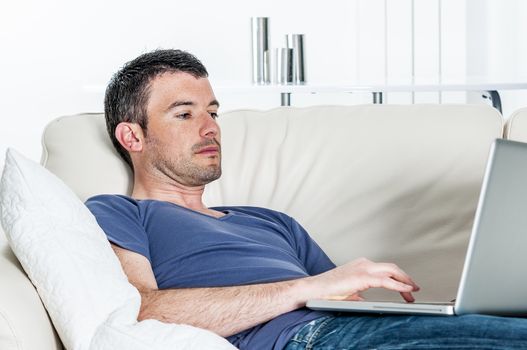 attractive relaxed man is working at home on a sofa