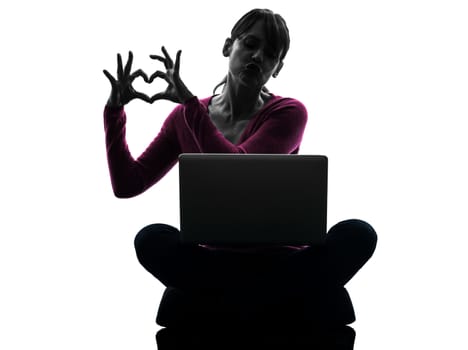 one caucasian woman heart gesture computing laptop computer  in silhouette studio isolated on white background