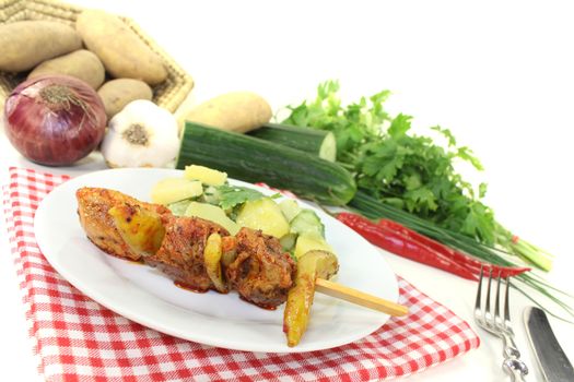 Potato-cucumber salad with fire skewers and chilli on a light background