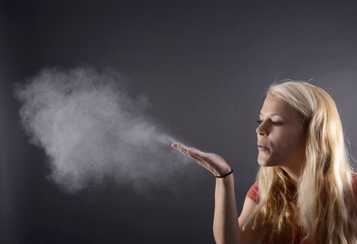 young blond woman blowing powder      