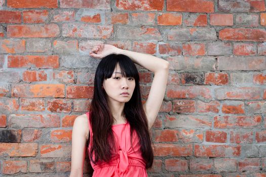 Chinese woman with sad expression by brick wall