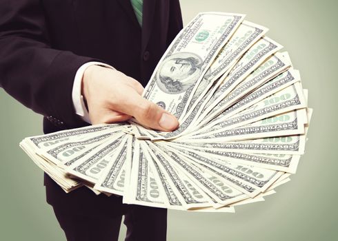 Business Man Displaying a Spread of Cash over Vintage Green Background 