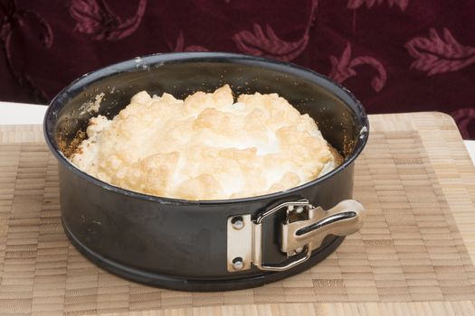 Meringue cake in a springform pan on a wooden board